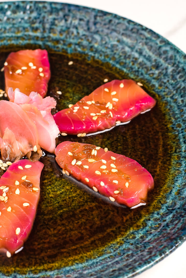 Sashimi with sesame and pickled ginger on a blue ceramic plate